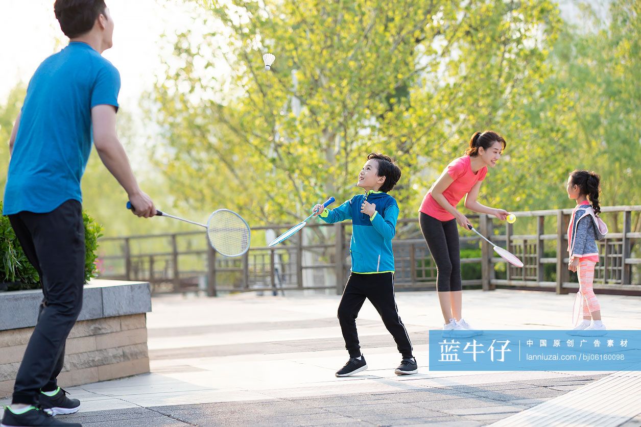 快乐的年轻家庭在公园打羽毛球