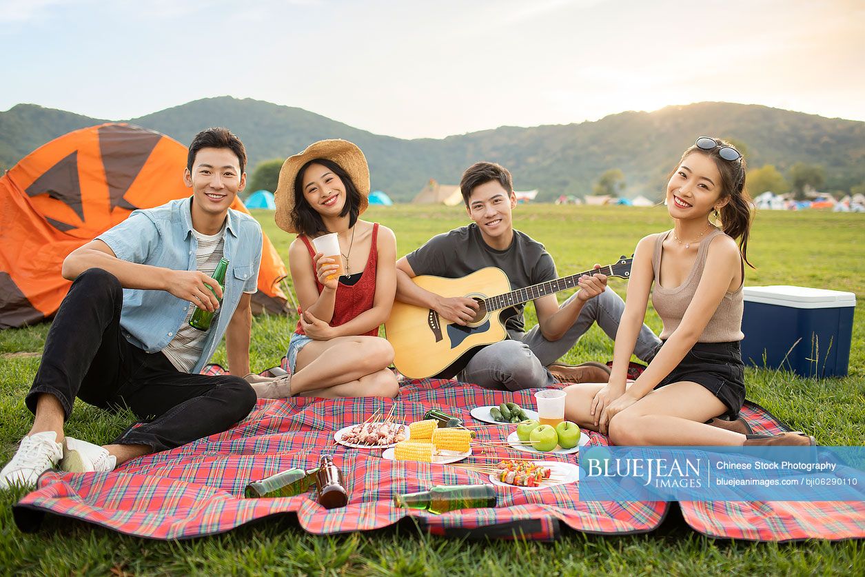Happy young Chinese friends having a picnic outdoors