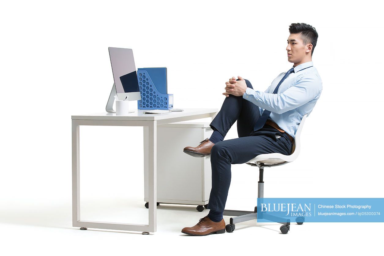 Young Chinese businessman exercising in office