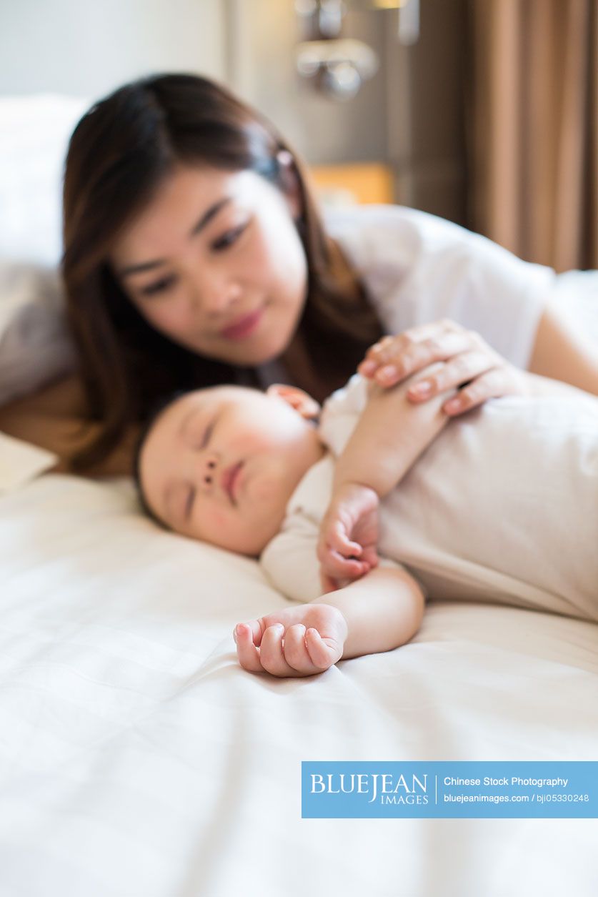 Young Chinese mother with sleeping baby boy