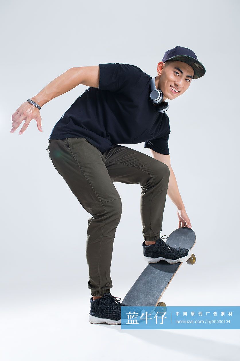 戴耳机的快乐年轻男子在滑滑板