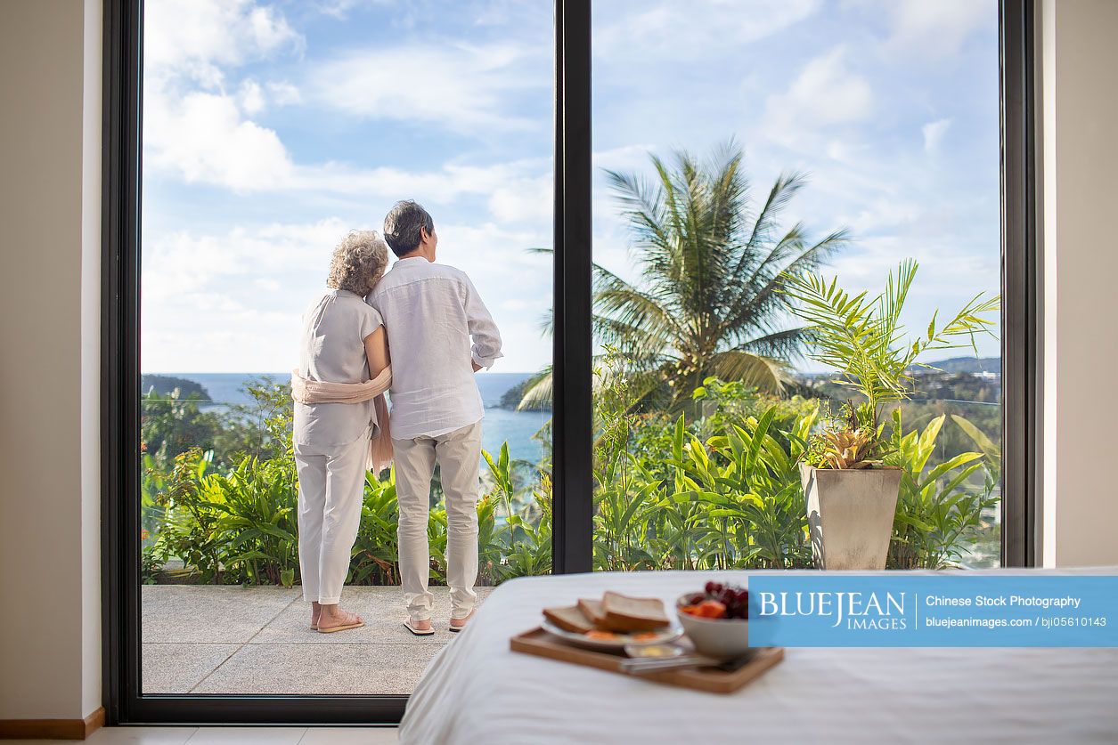 Happy senior Chinese couple relaxing on balcony