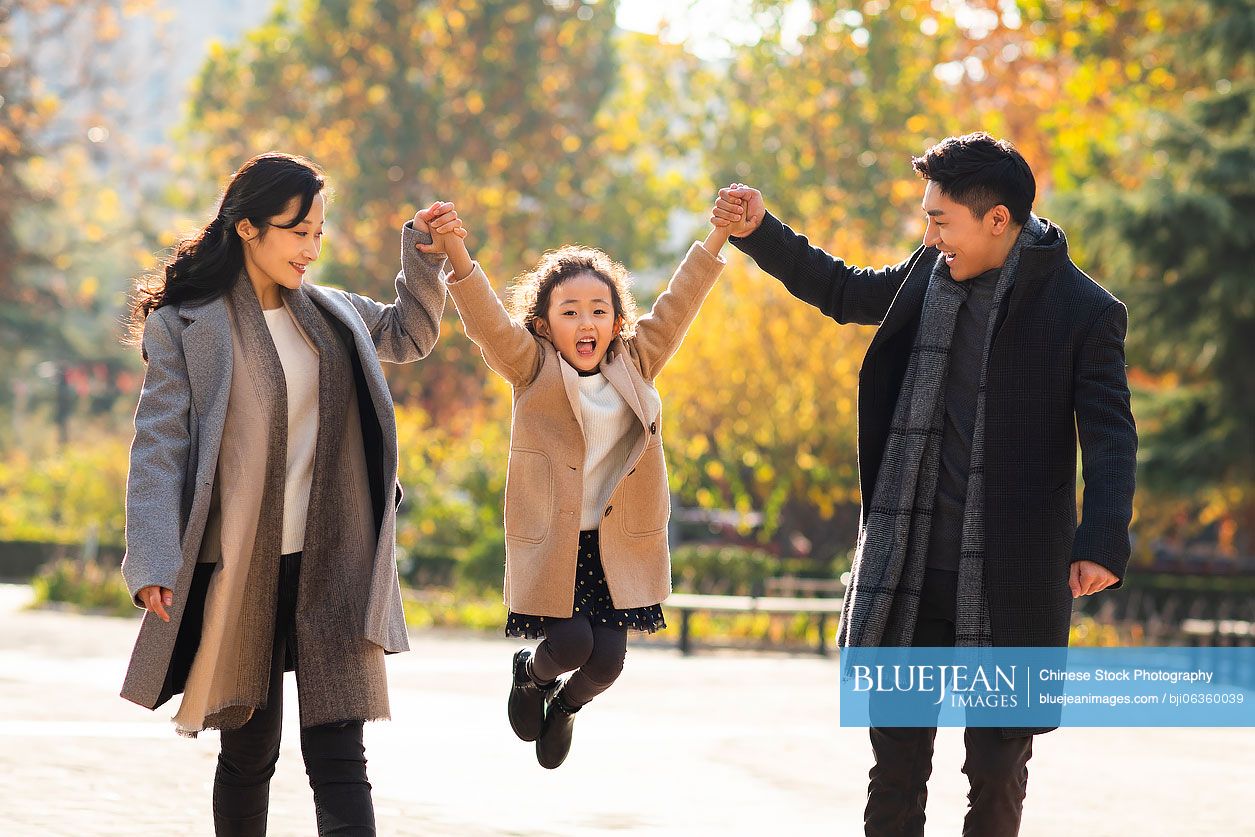 Happy young Chinese family having fun in park