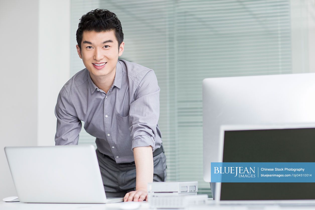 Young Chinese businessman using laptop in office