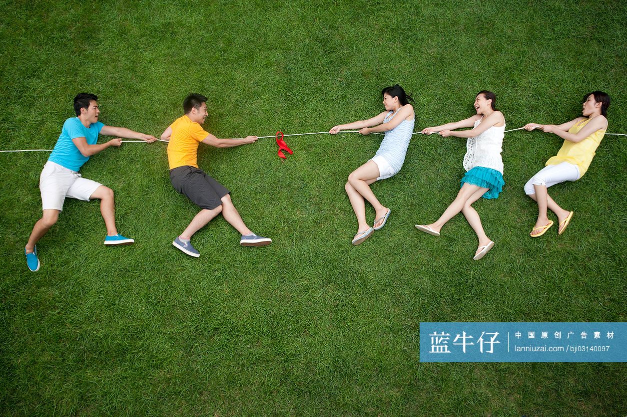 创意男女在草地上模仿拔河