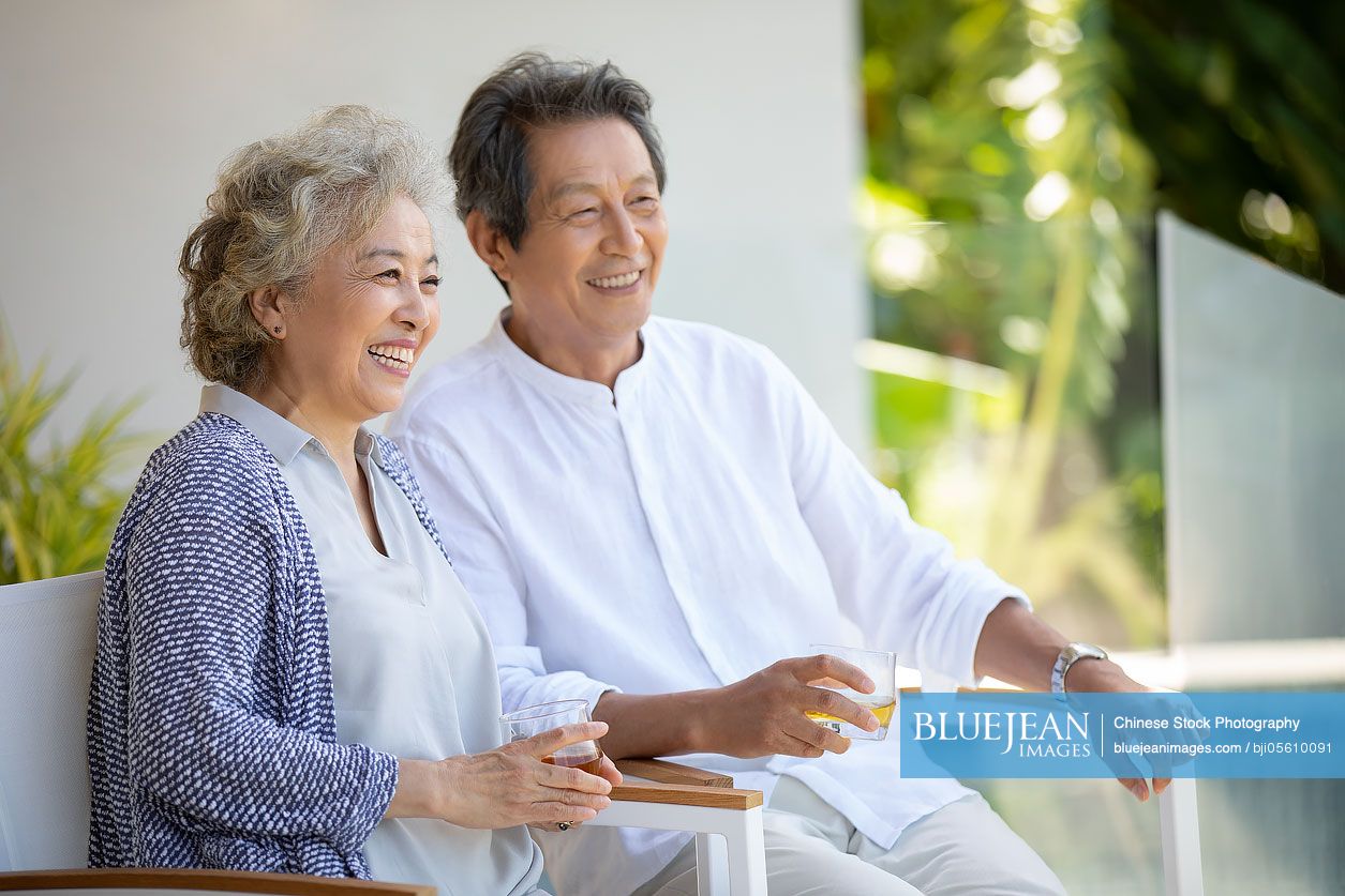 Happy senior Chinese couple relaxing on balcony