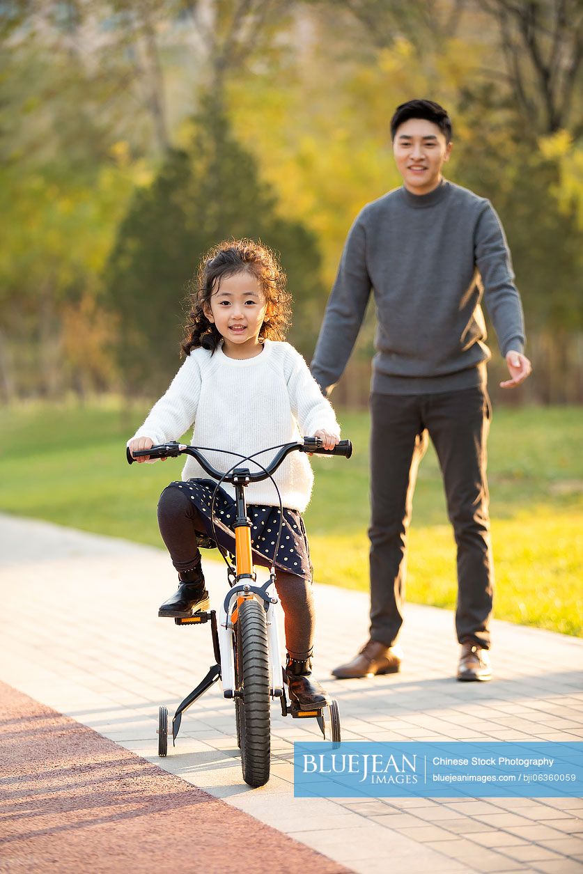 Chinese father teaching daughter how to ride bike