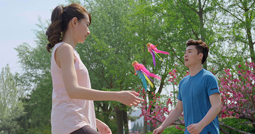 Happy young Chinese couple kicking shuttlecock in park,4K