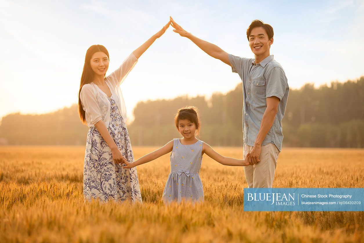 Happy young Chinese family having fun in wheat field
