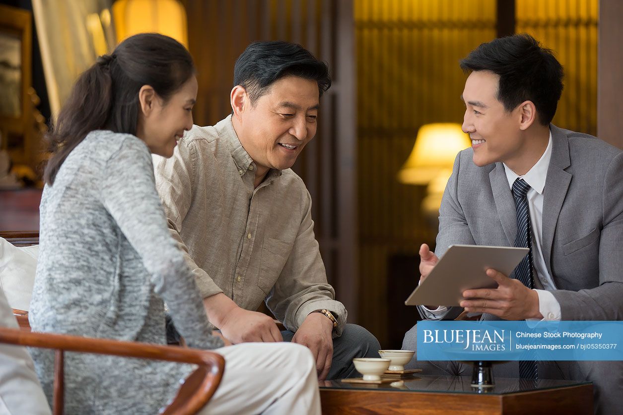 Confident Chinese financial consultant talking with mature couple