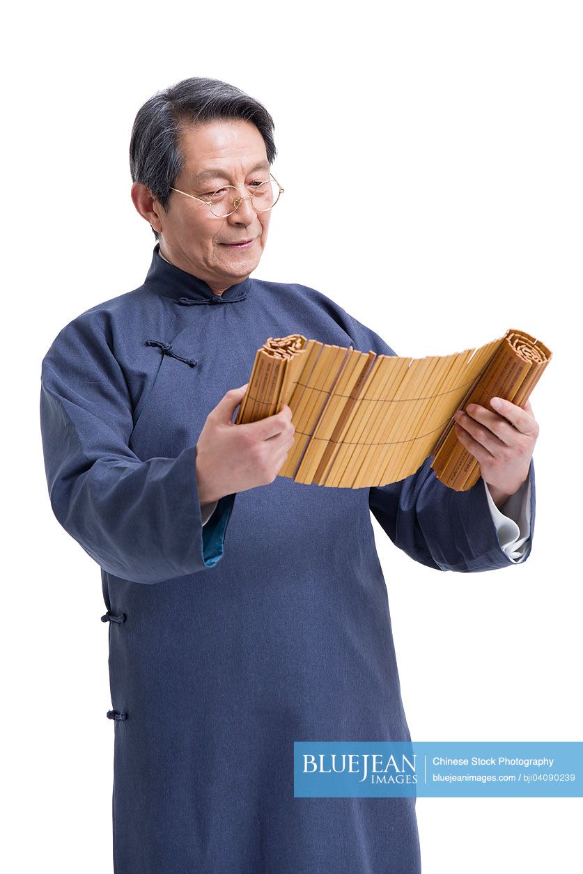 Senior Chinese teacher in traditional clothing reading bamboo slips