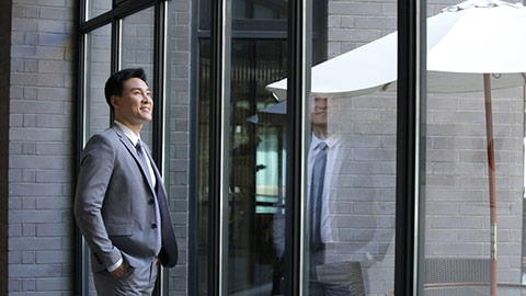 Confident Chinese businessman looking through window,HD