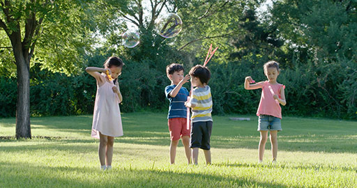 快乐儿童在草坪上吹泡泡