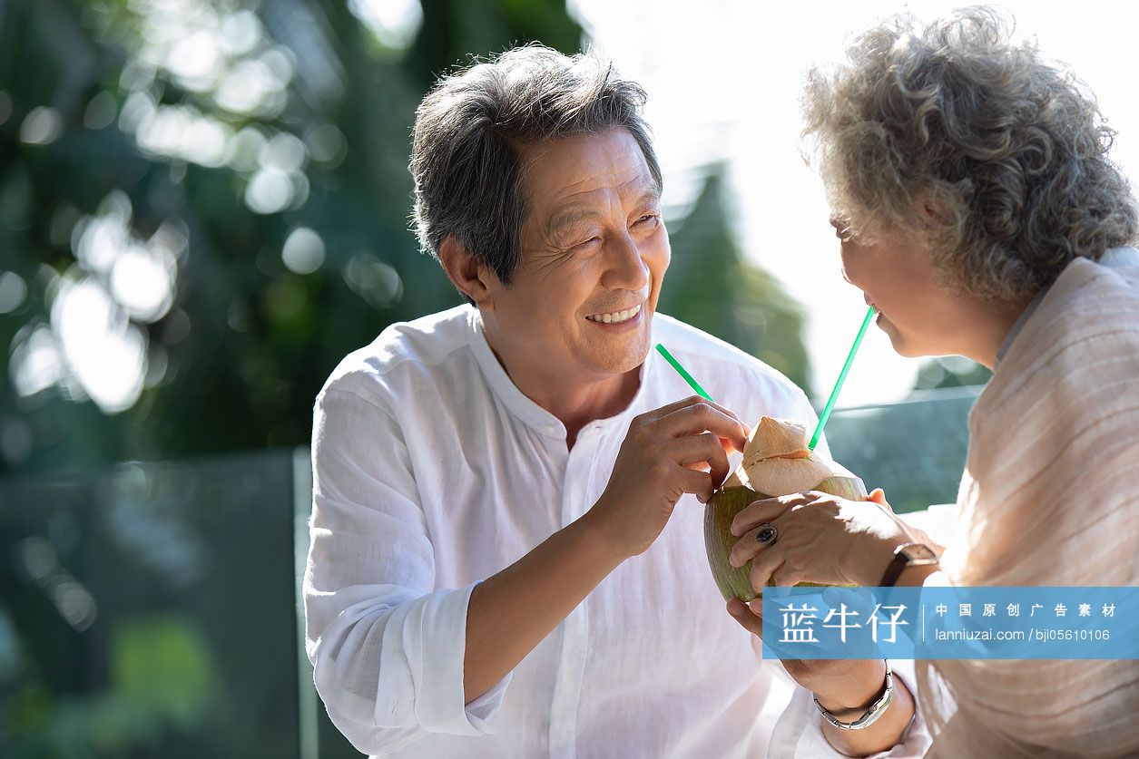 快乐的老年夫妇在阳台喝椰汁