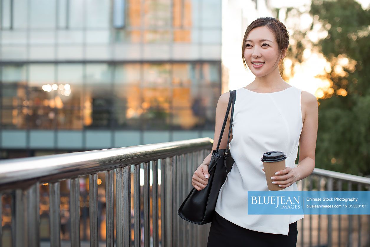 Confident young Chinese businesswoman holding  a cup of coffee