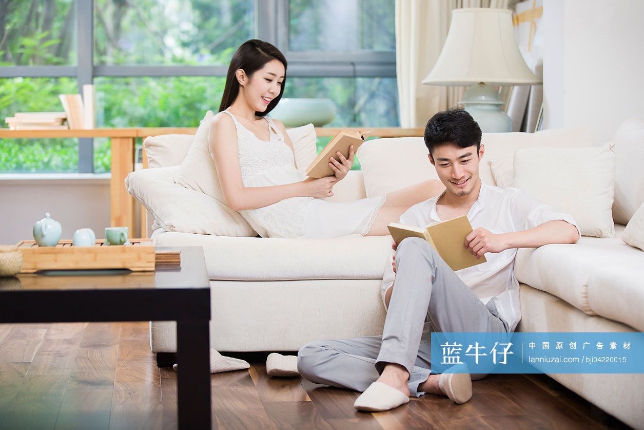 快乐的年轻情侣在客厅看书