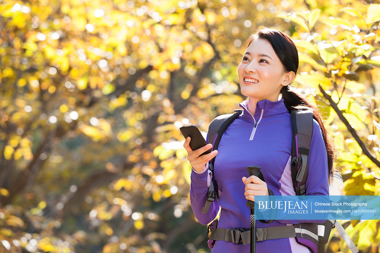 Happy female Chinese backpacker with smart phone