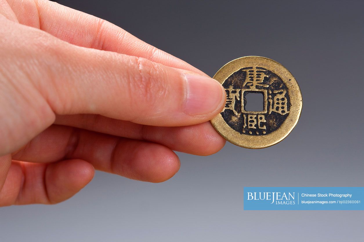 Hand holding traditional Chinese coin