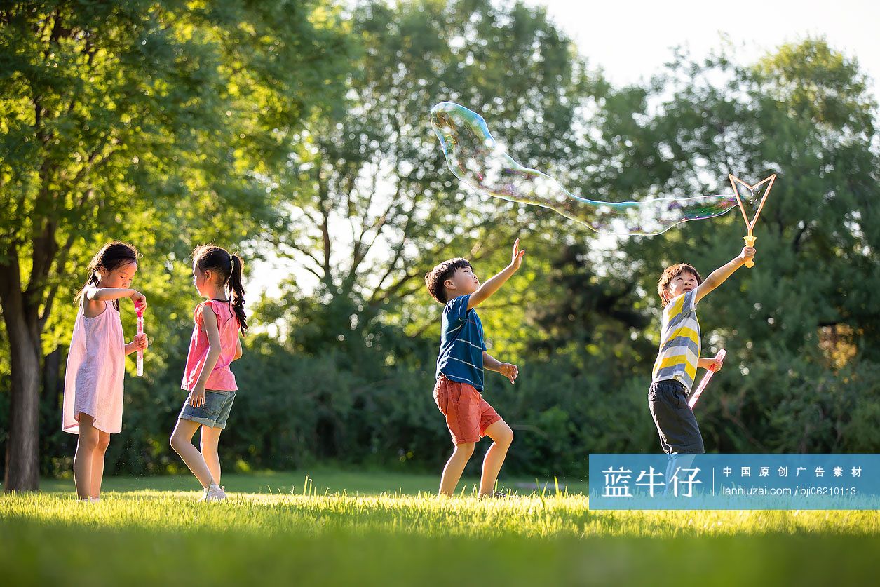 快乐的儿童在草地上吹泡泡