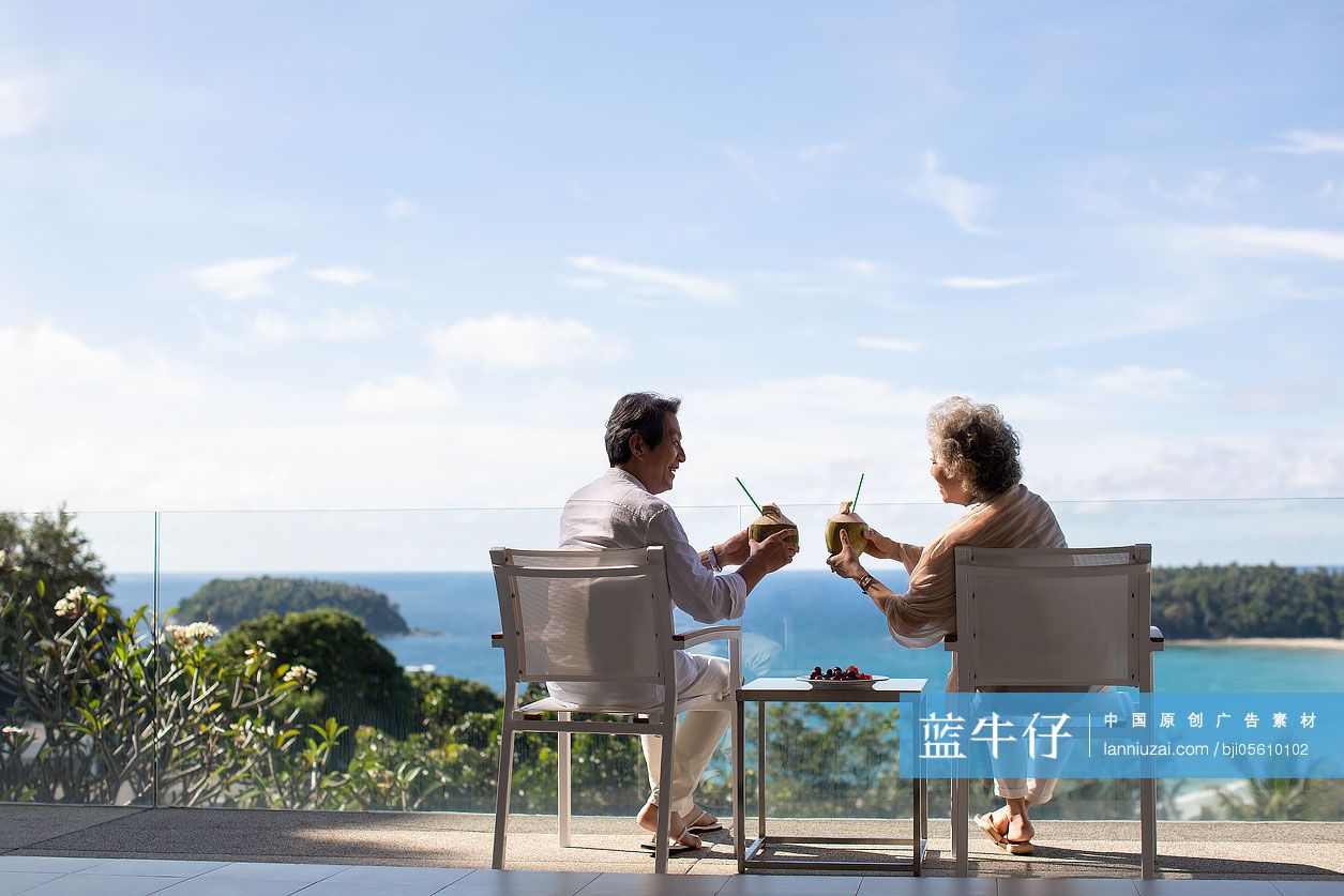 快乐的老年夫妇在阳台喝椰汁