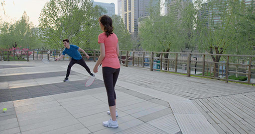 快乐的年轻情侣在公园打羽毛球