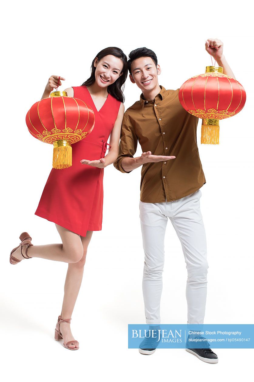 Cheerful young couple celebrating Chinese new year with traditional lanterns
