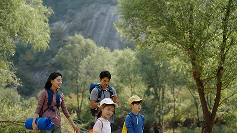 Happy young Chinese family hiking outdoors