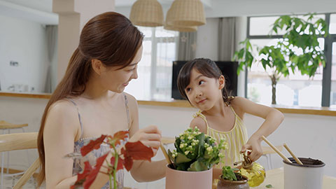 Mum and daughter enjoy potting plants together at home