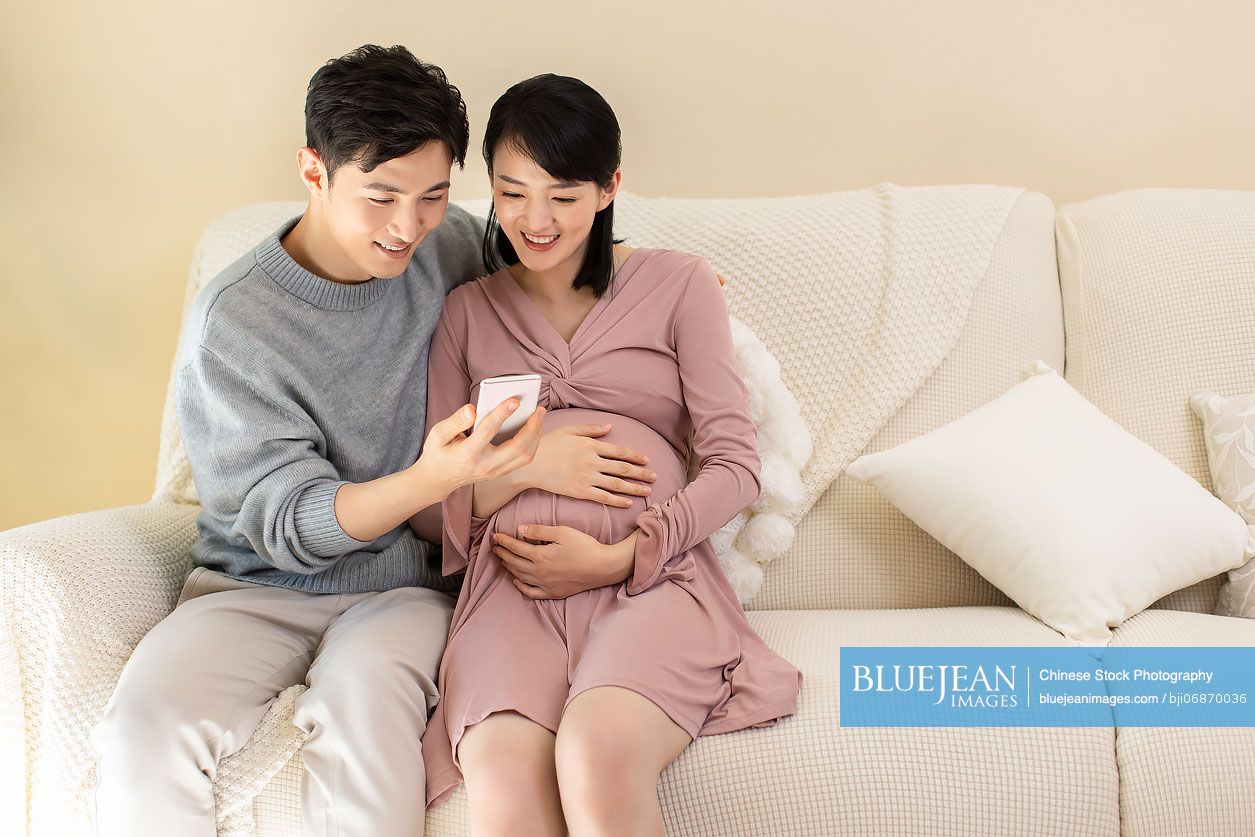 Young Chinese pregnant woman with husband shopping online