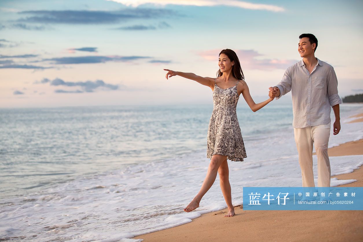 快乐的年轻夫妇在沙滩散步