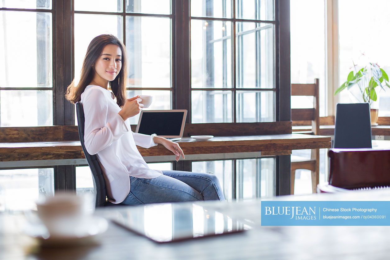 Young Chinese woman drinking coffee in cafe