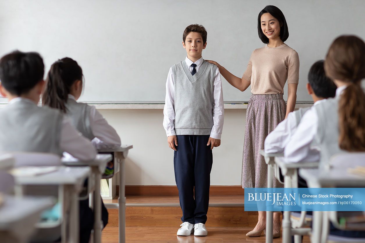 Young Chinese teacher introducing a new classmate in classroom