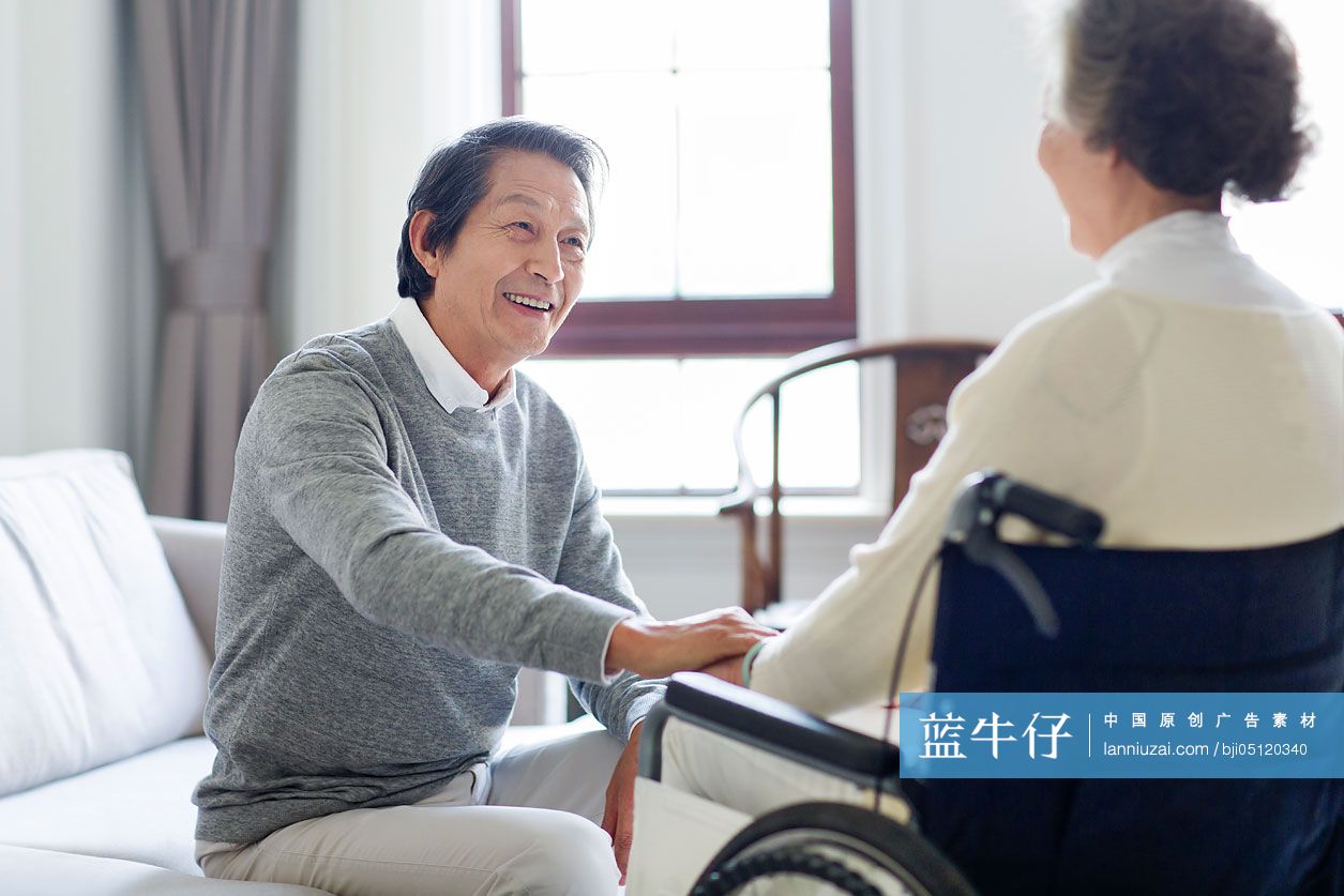 老年男子照顾坐着轮椅的妻子