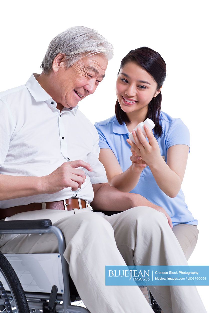 Female Chinese nursing worker showing senior man medicine