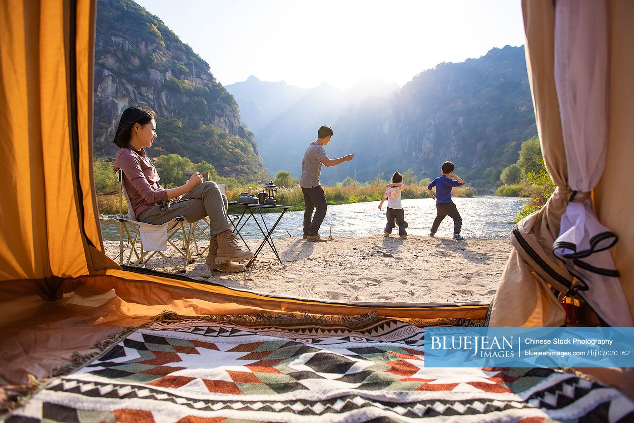 Happy young Chinese family camping outdoors