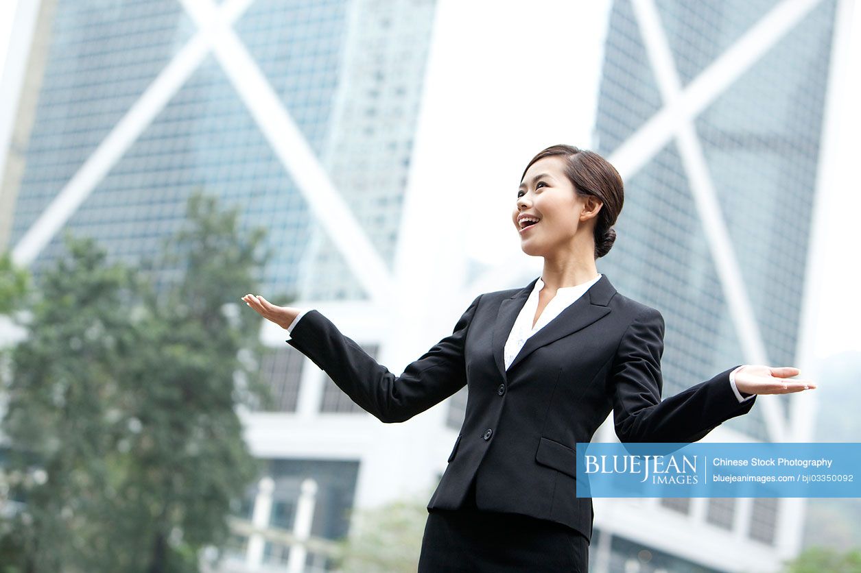 Cheerful Chinese businesswoman arms outstretched, Hong Kong