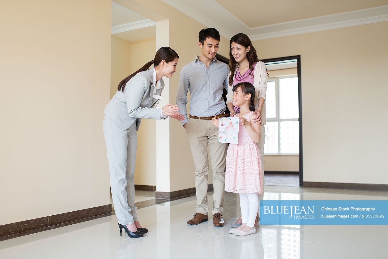 Cute little Chinese girl showing her drawing to realtor