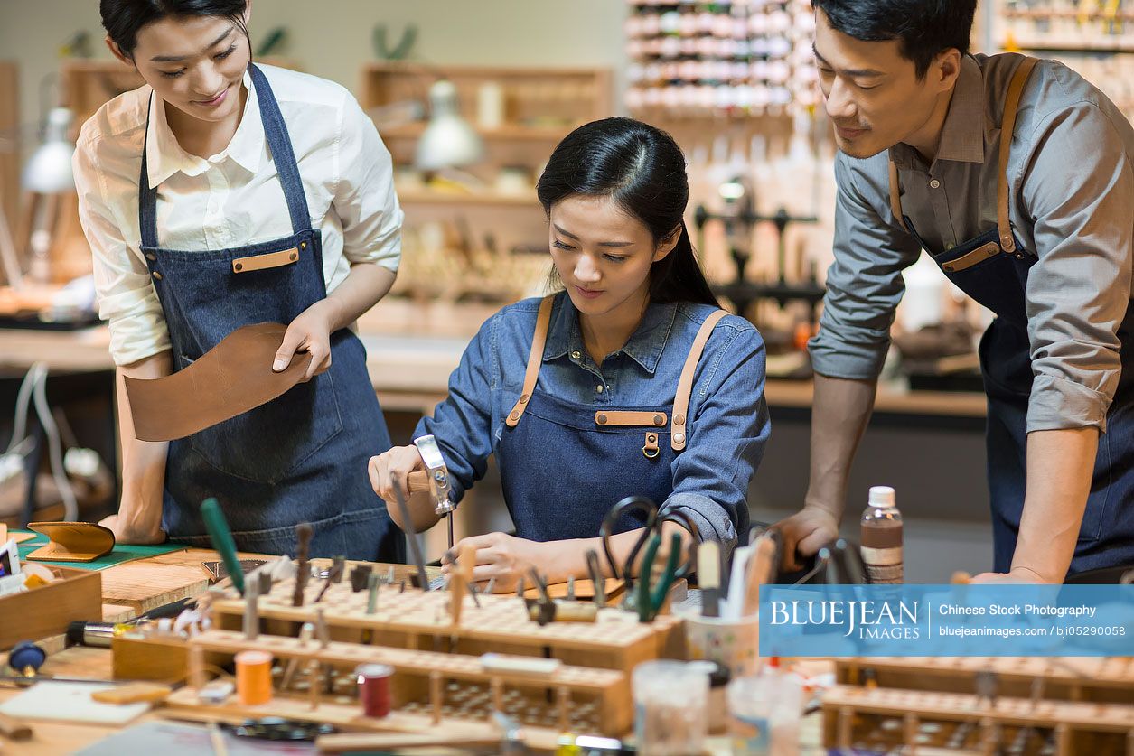 Young Chinese leather craftspeople working in studio 