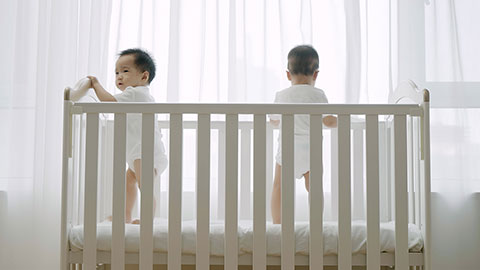 Two twin babies playing in their crib