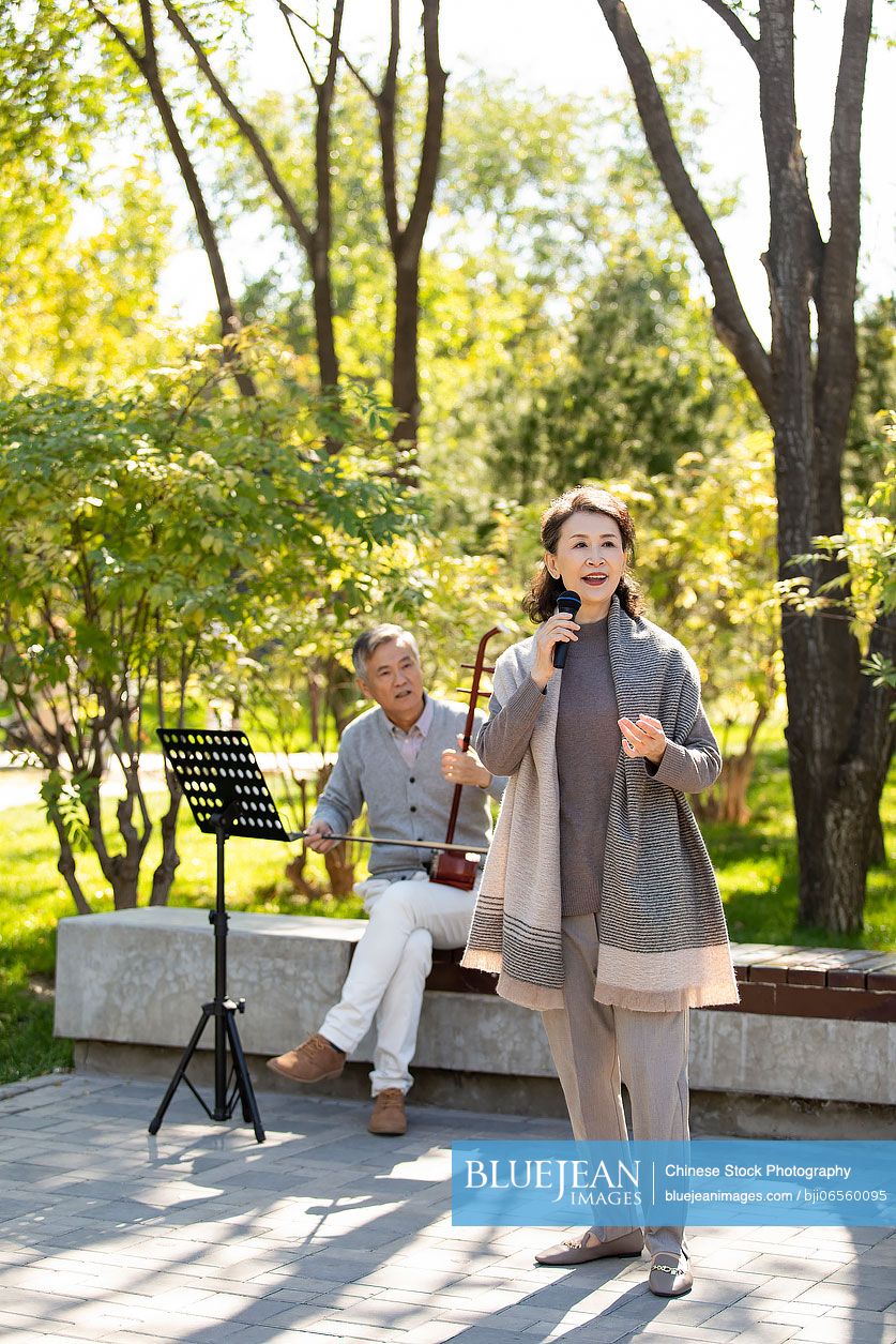 Cheerful senior Chinese woman singing with microphone