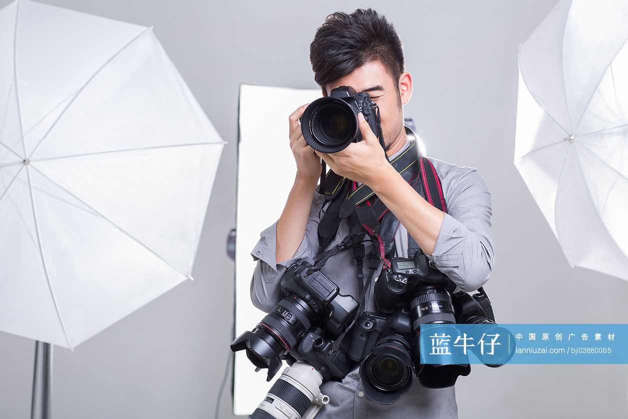 一个摄影师拿着很多相机拍照