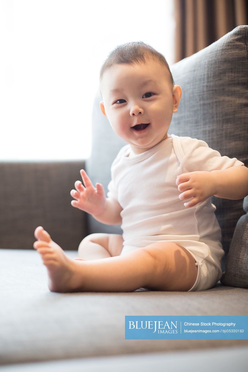 Cute Chinese baby boy sitting on sofa