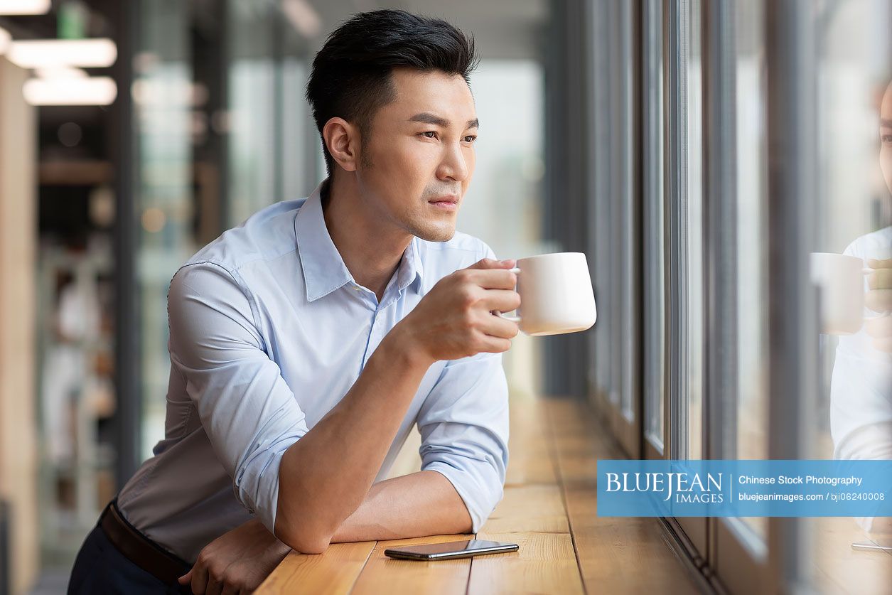 Chinese businessman drinking coffee in café