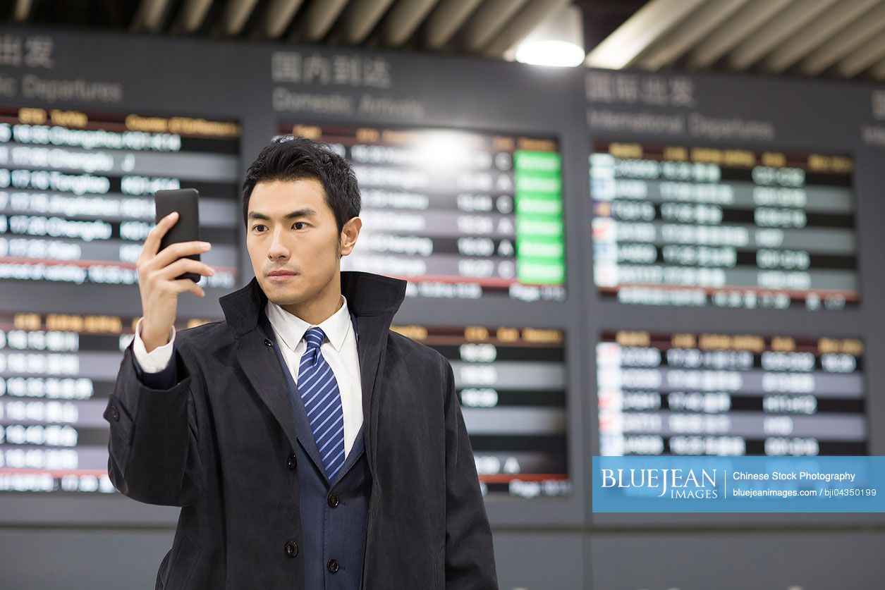 Young Chinese businessman using smart phone in airport