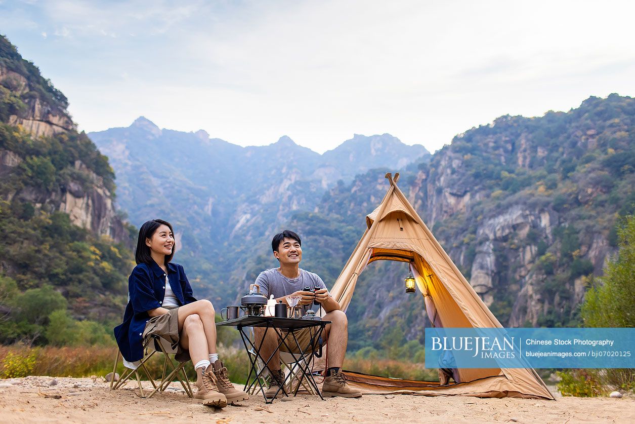 Happy young Chinese couple camping outdoors