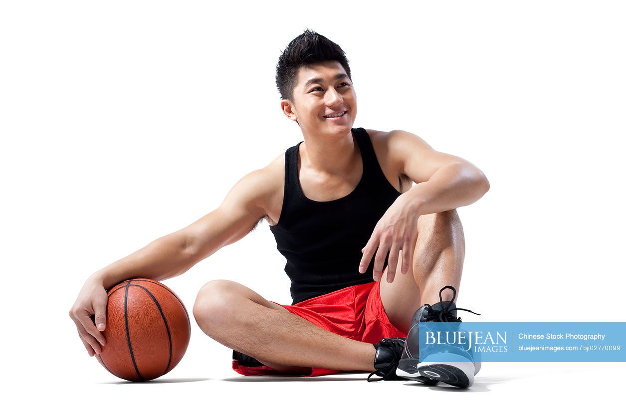 Chinese man sitting on the floor with basketball