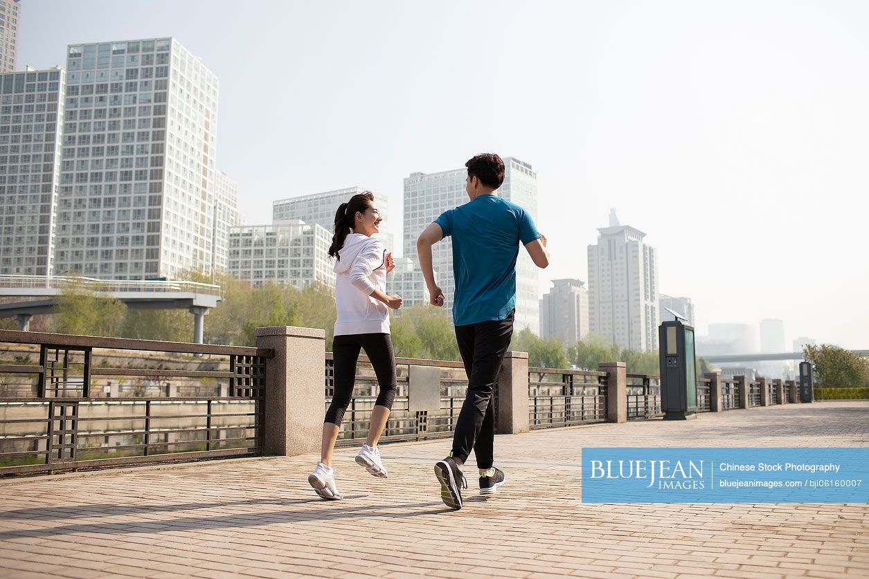 Happy young Chinese couple running in park
