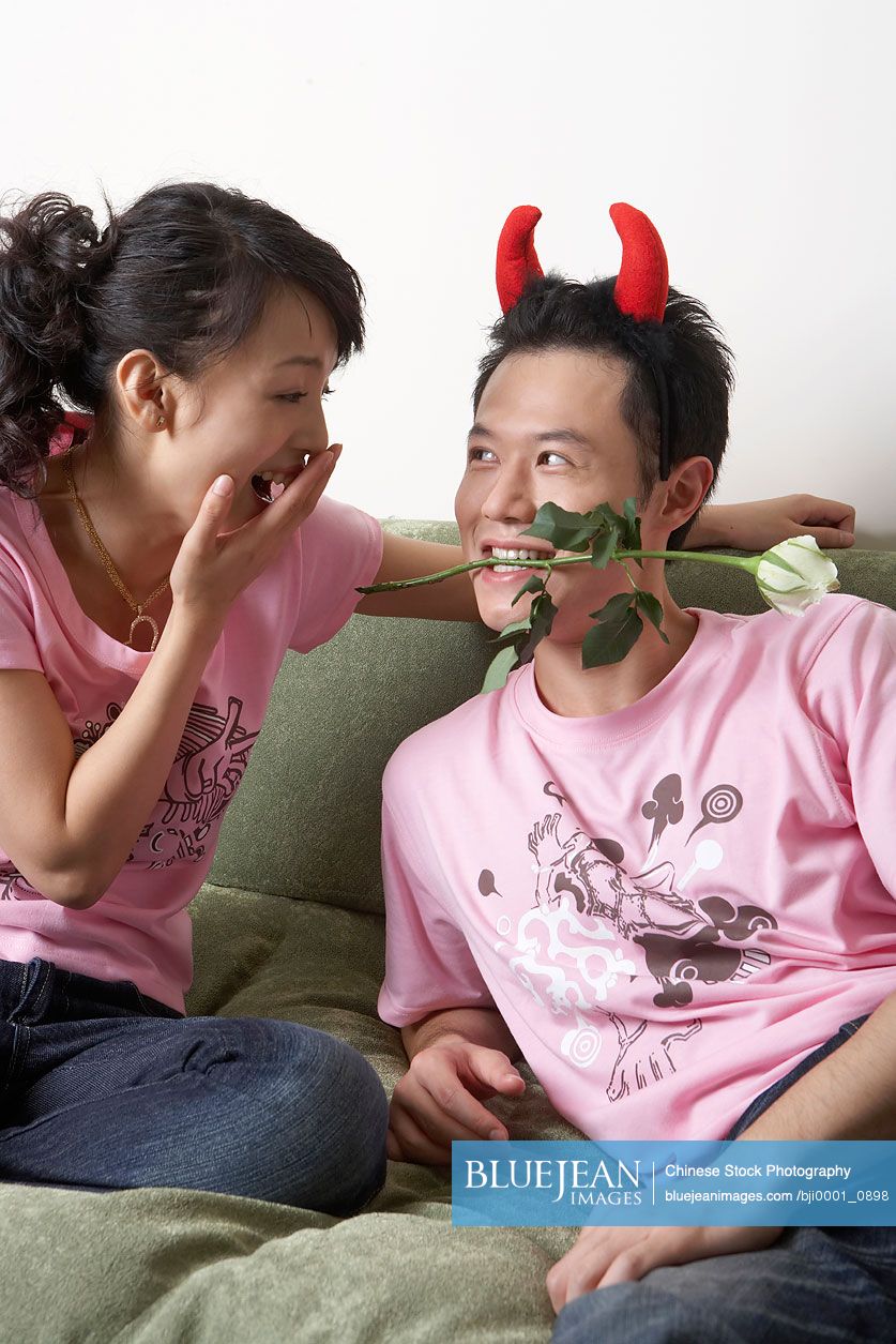 Chinese man Wearing Devil Horns, Holding Rose In His Teeth