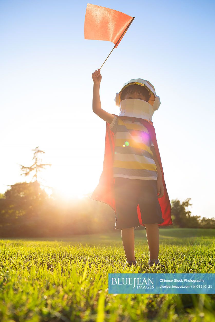 Little Chinese boy in costume playing on meadow