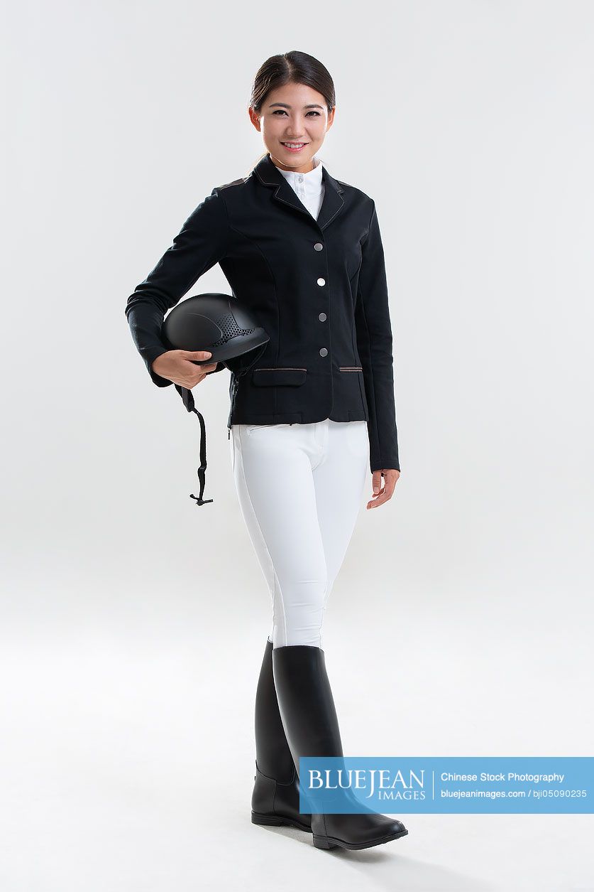 Happy young Chinese woman in riding clothes